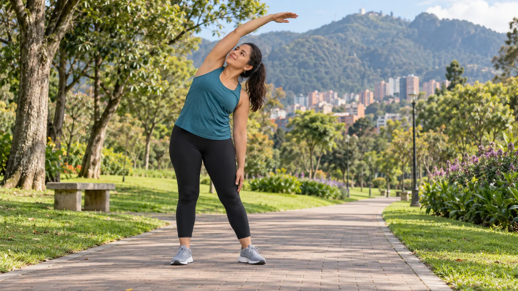 Mujer latinoamericana haciendo un estiramiento lateral suave durante una caminata en un parque de Bogotá